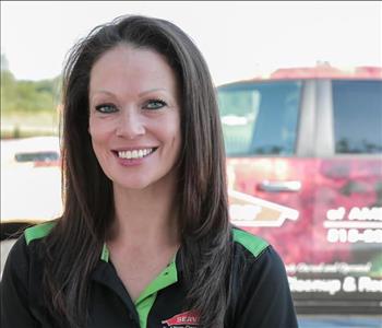 Female employee Lori Newhouse in front of SERVPRO truck in background